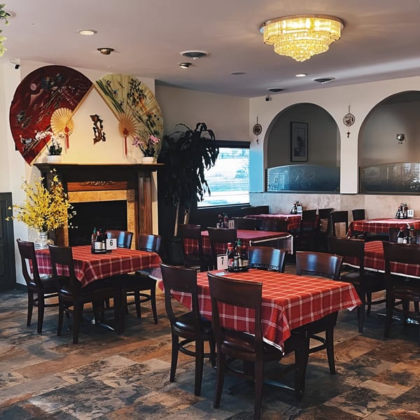 Interior of Pho Vietnam restaurant with red checkered tables, dark chairs, and decorative fans on the wall.