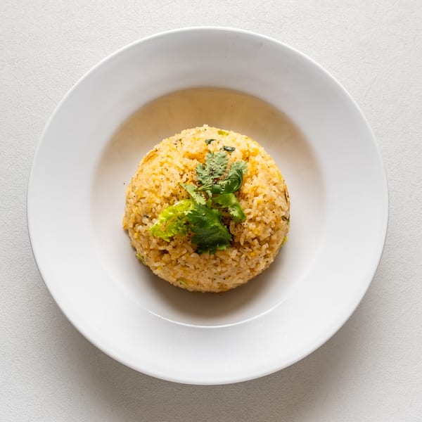 Vietnamese fried rice with cilantro and black pepper, served in a white bowl.