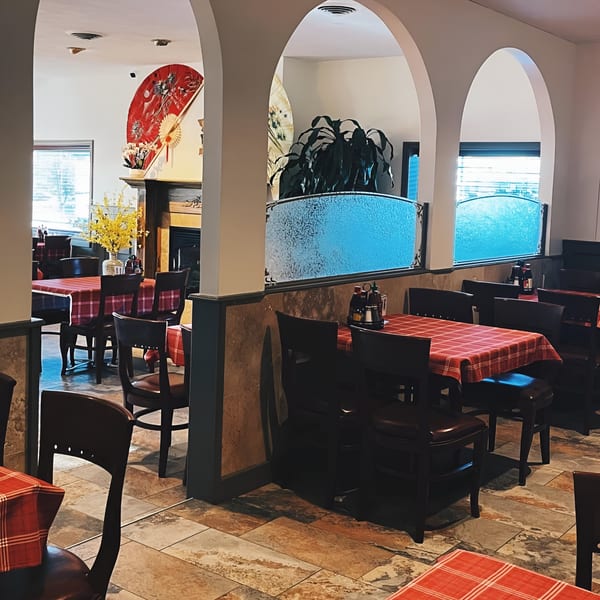 Dining room at Pho Vietnam with red checkered tablecloths, dark chairs, and decorative arches.