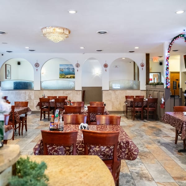 Interior of Pho Vietnam restaurant with empty tables, red chairs, and decorative archways.